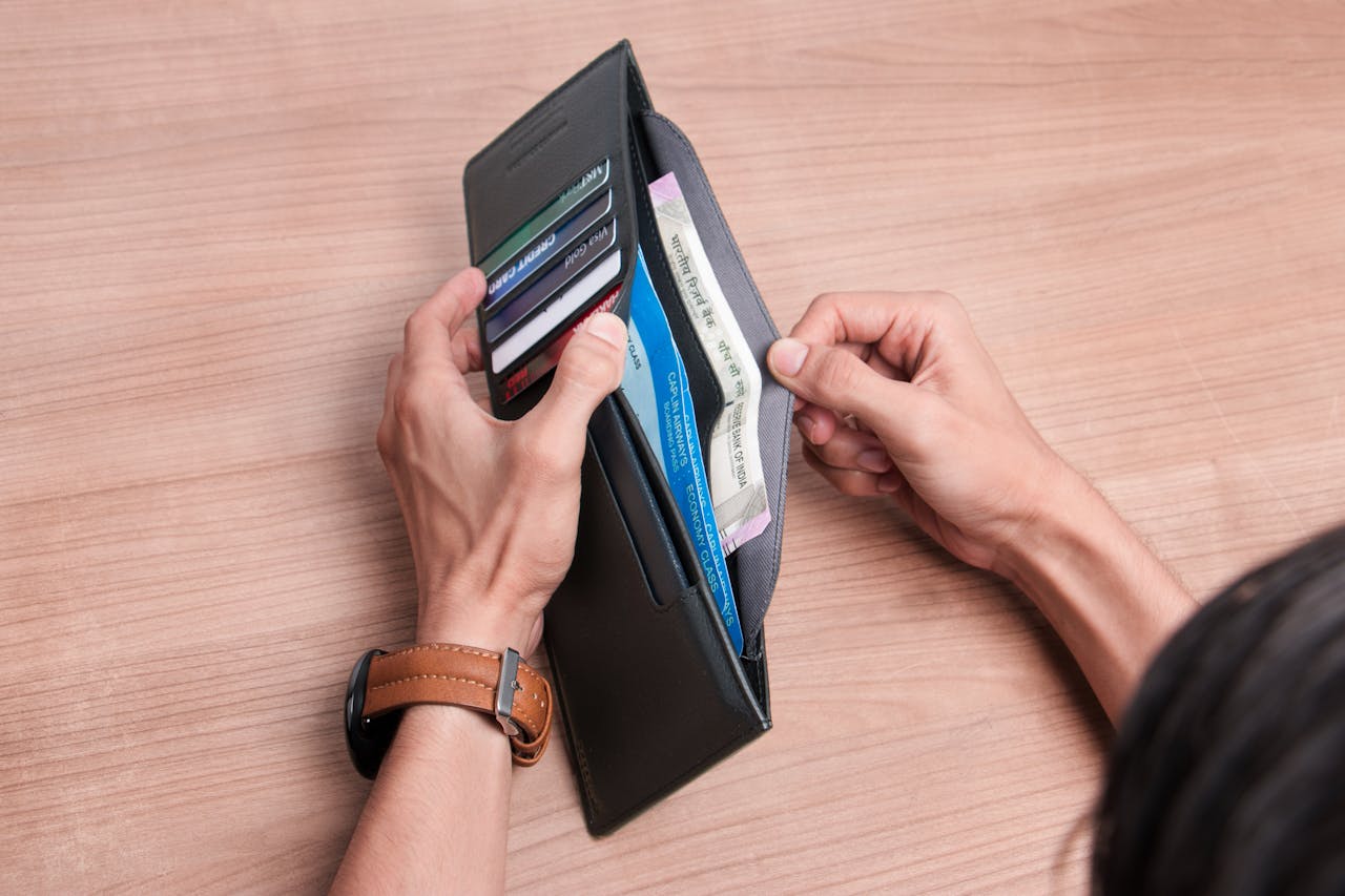 why-choose-us Close-up of a person managing a wallet with cash and cards on a wooden table.