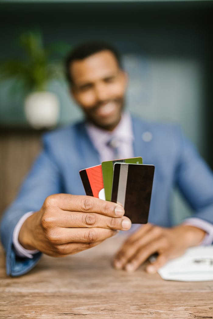 Services-03 Professional man in suit holding multiple credit cards, emphasizing finance and business concept.